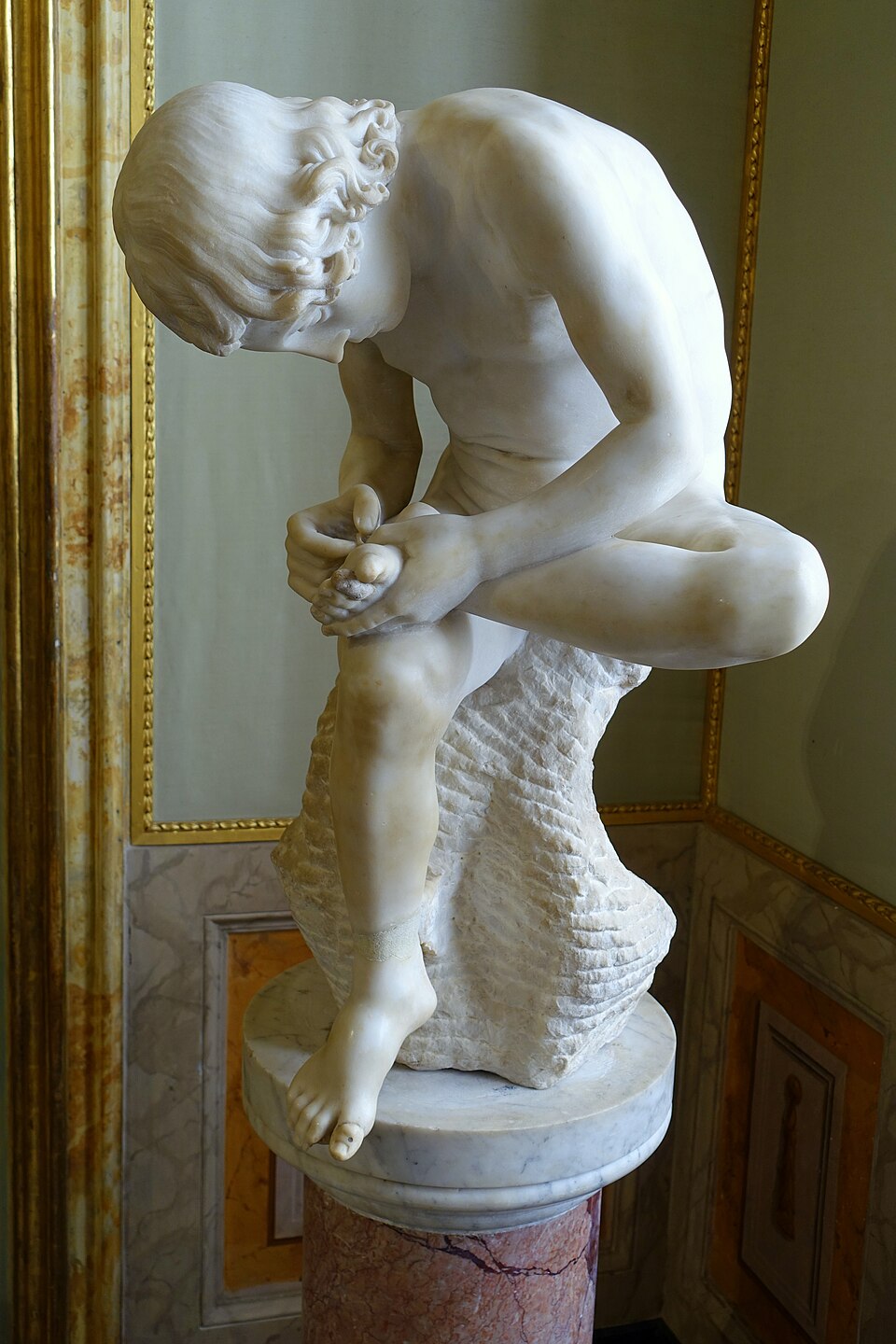 Le Tireur d’épine, sculpture de Sculpteur romain anonyme : Un jeune garçon assis se penche pour retirer une épine de la plante de son pied