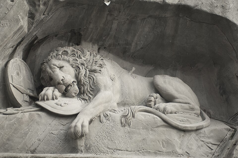 Lion de Lucerne, sculpture de Bertel Thorvaldsen (conception), Lukas Ahorn : Un lion mourant repose dans une niche rocheuse, au-dessus d’un…